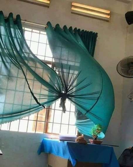 Комната с висящим голубым тканевым занавесом/гибким элементом, создающим развевающуюся форму