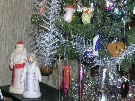 Новогодняя ёлка с гирляндами и фигурками Деда Мороза на полке