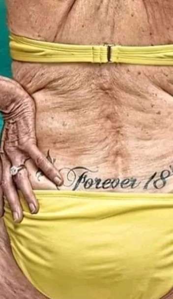 Обнажённая спина взрослого человека в жёлтом купальнике; на коже татуировка «Forever 18»