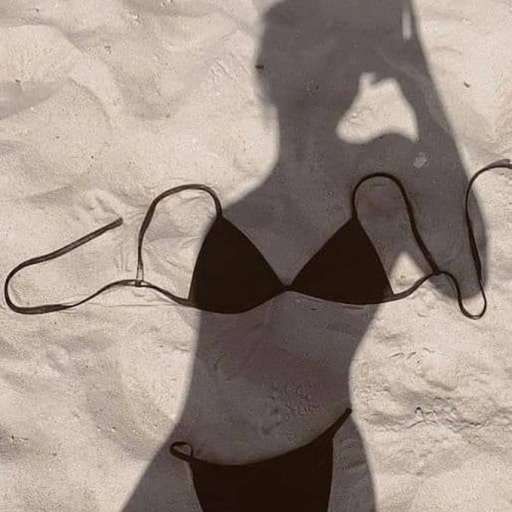 Силуэт женщины в купальнике на песке, тень руки держит камеру