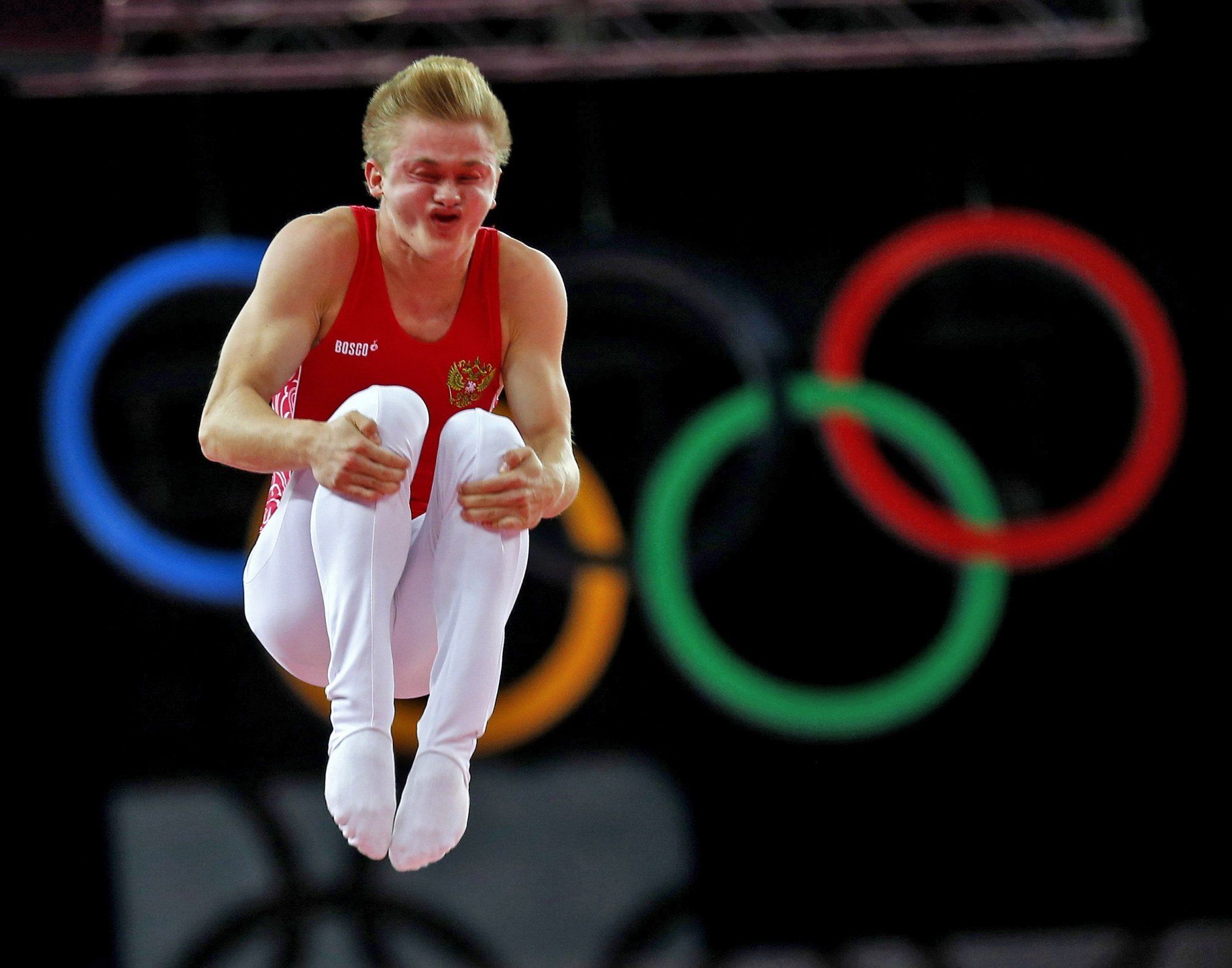 Спортсмен-прыгун на фоне олимпийских колец