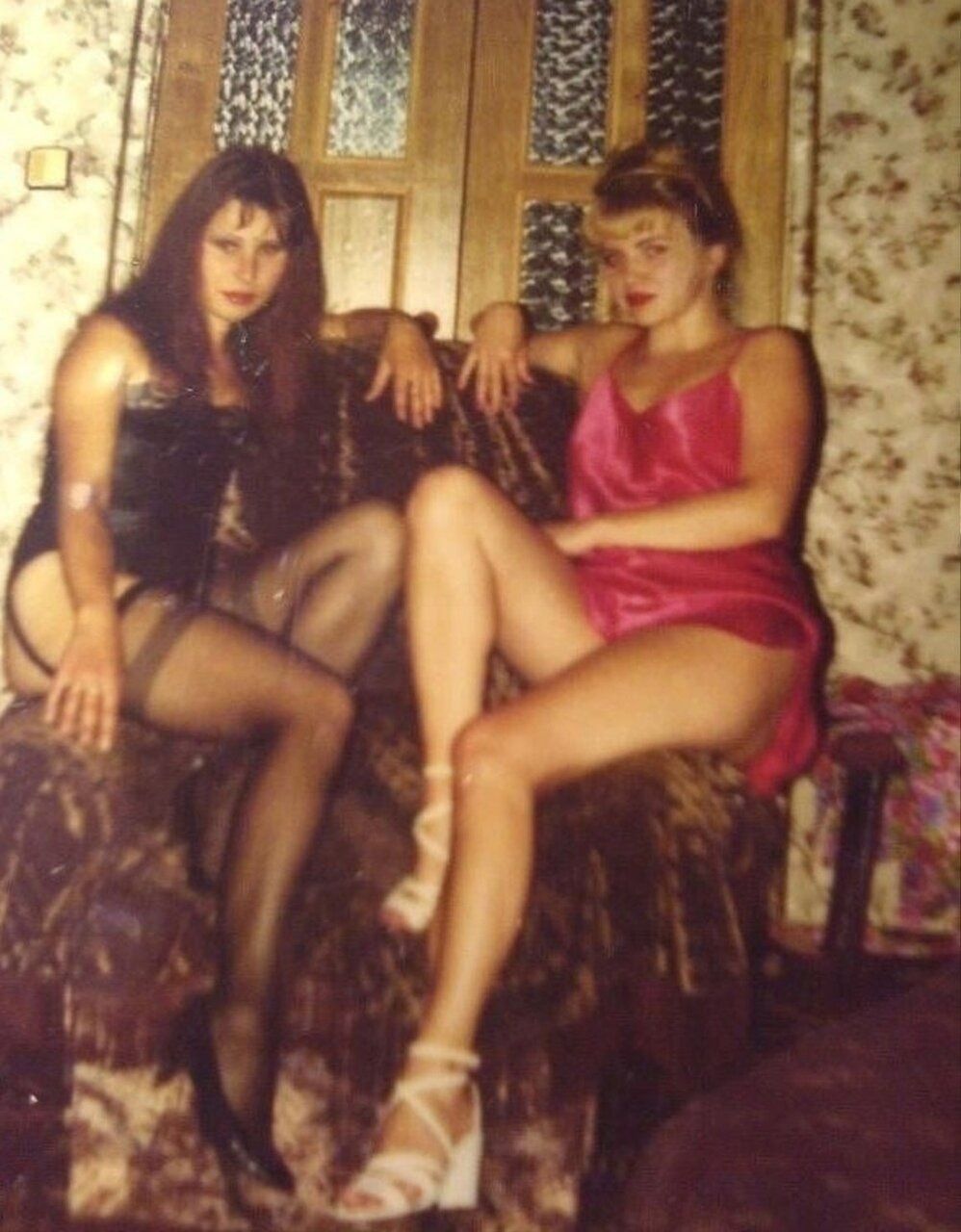 Две женщины в сексуальных нарядах посреди домашней обстановки.