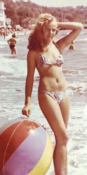 Девушка в купальнике на пляже держит большой надувной мяч near берегу моря