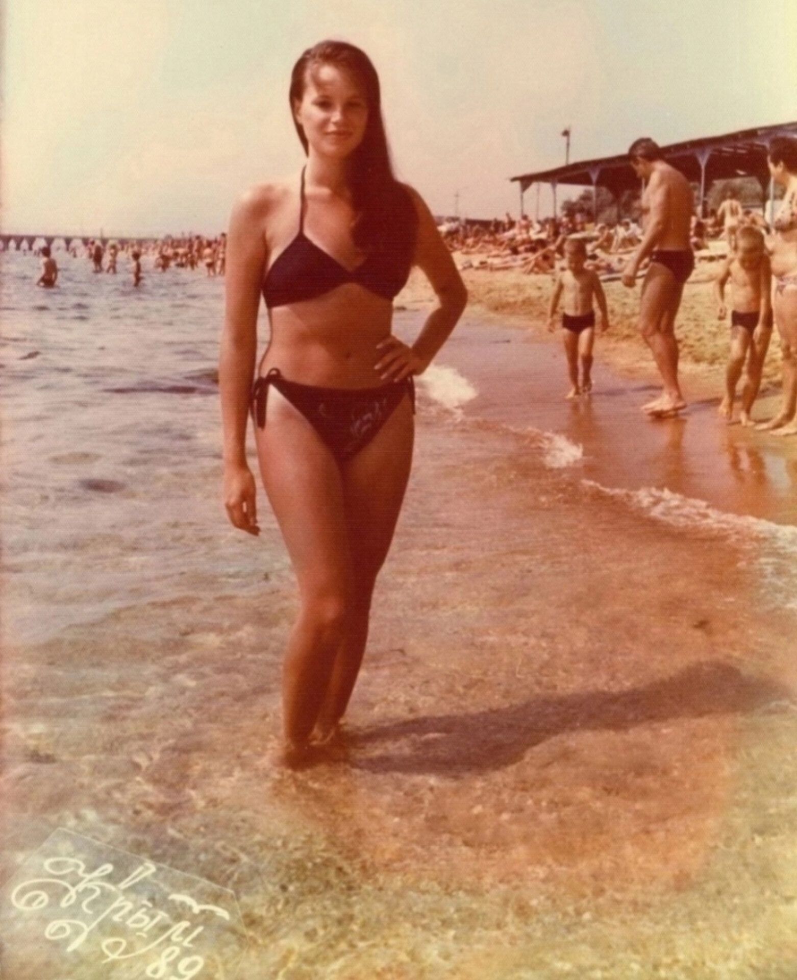 Девушка в бикини на берегу пляжа,люди на заднем плане