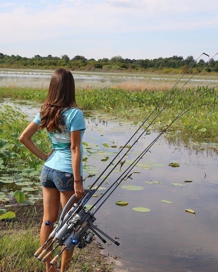 Женщина у водоема с несколькими удочками, готовится к рыбалке.
