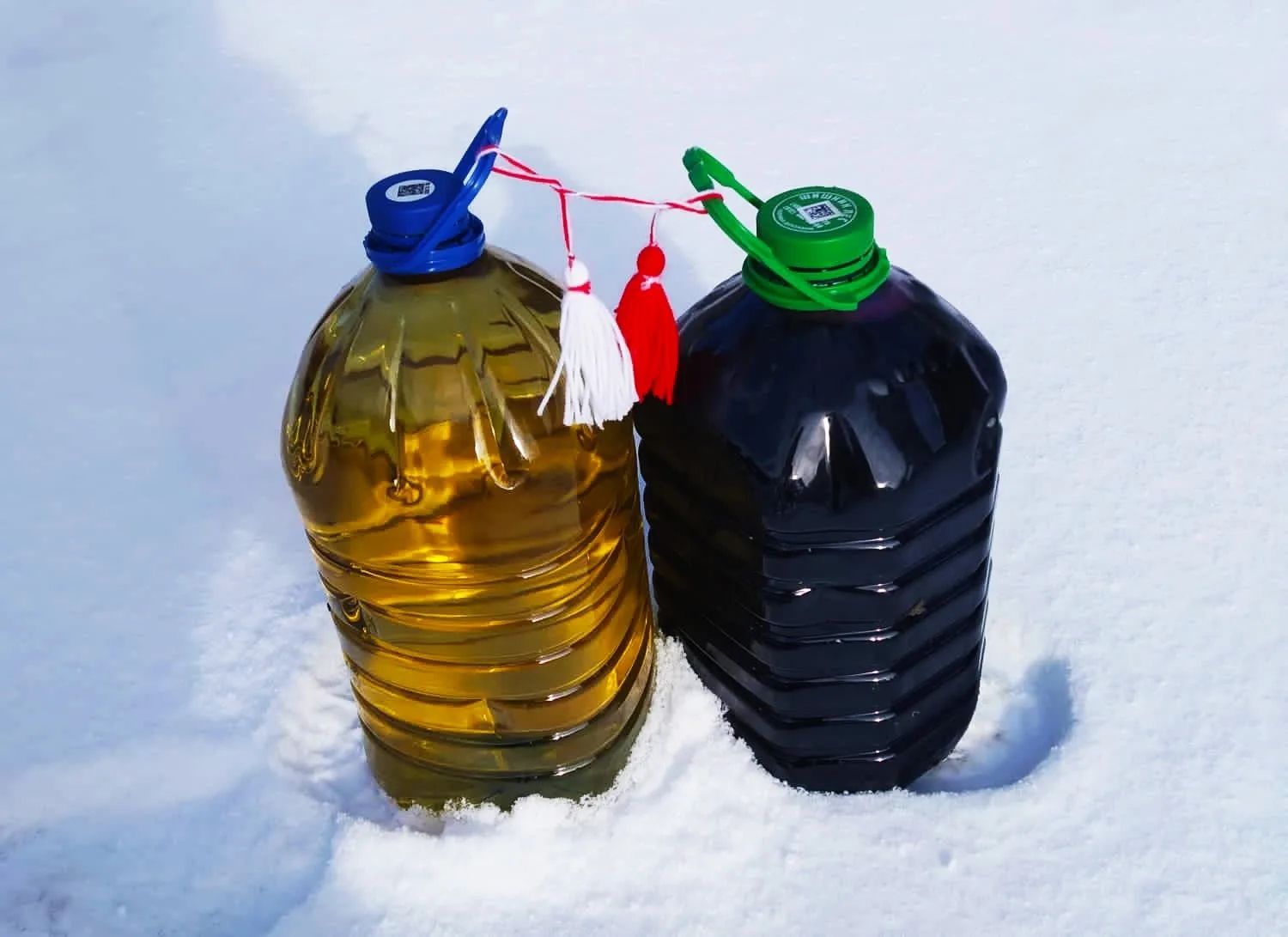 Две канистры с жидкостью в снегу, связка ярких крышек и верёвочных украшений.