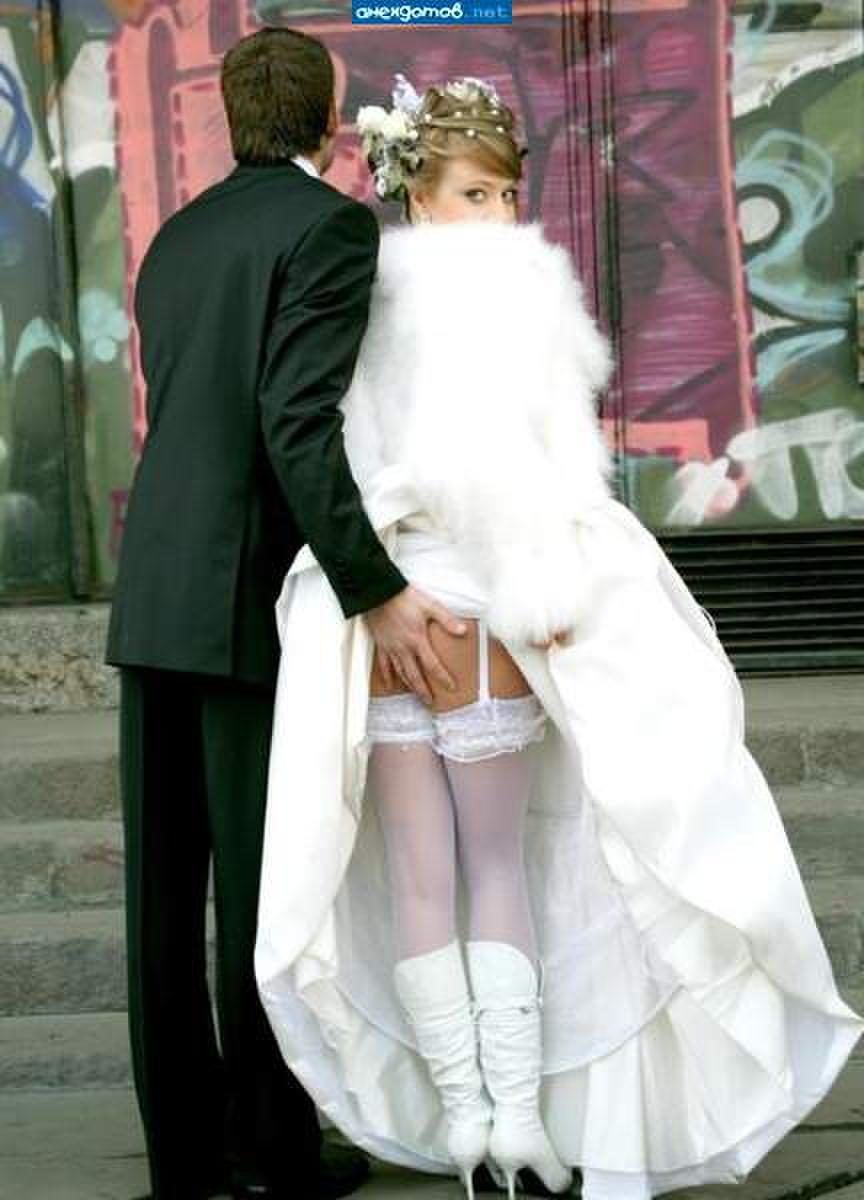 Мужчина в костюме касается ягодиц женщины в свадебном платье, позади граффити.