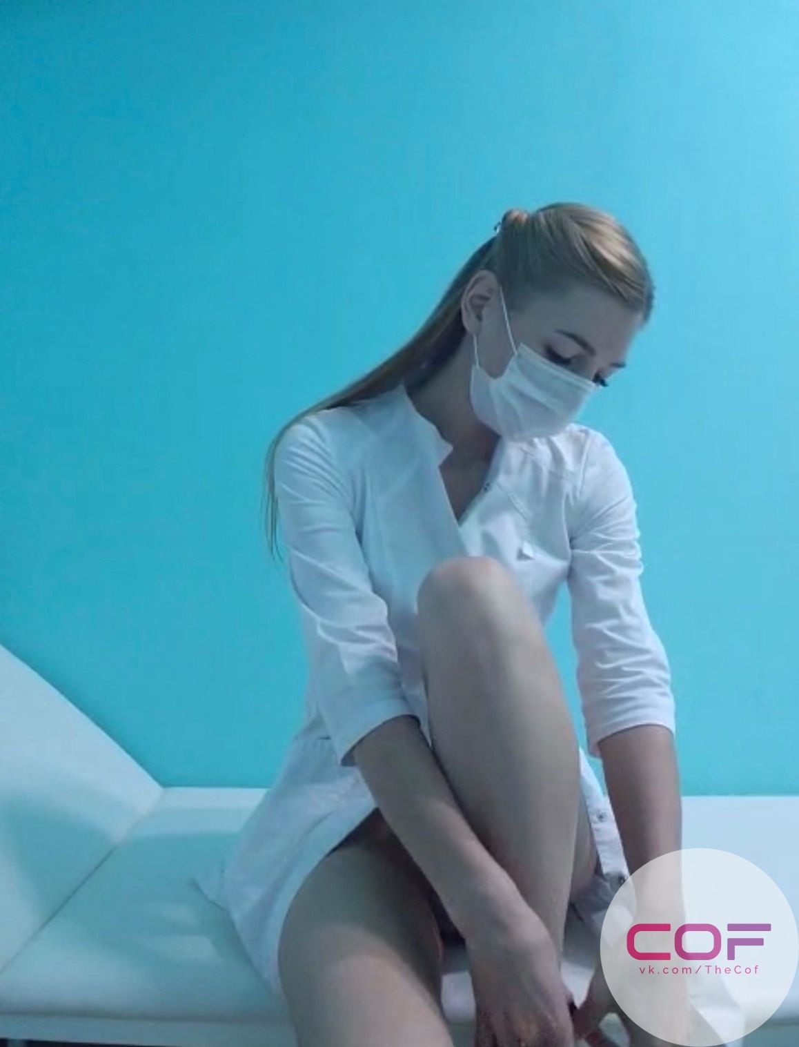 Женщина в белой рубашке в маске сидит на диване на голубом фоне