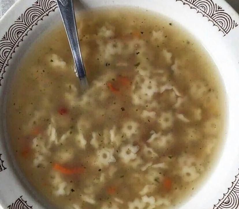 Бульонный суп с овощами и макаронами в тарелке с ложкой