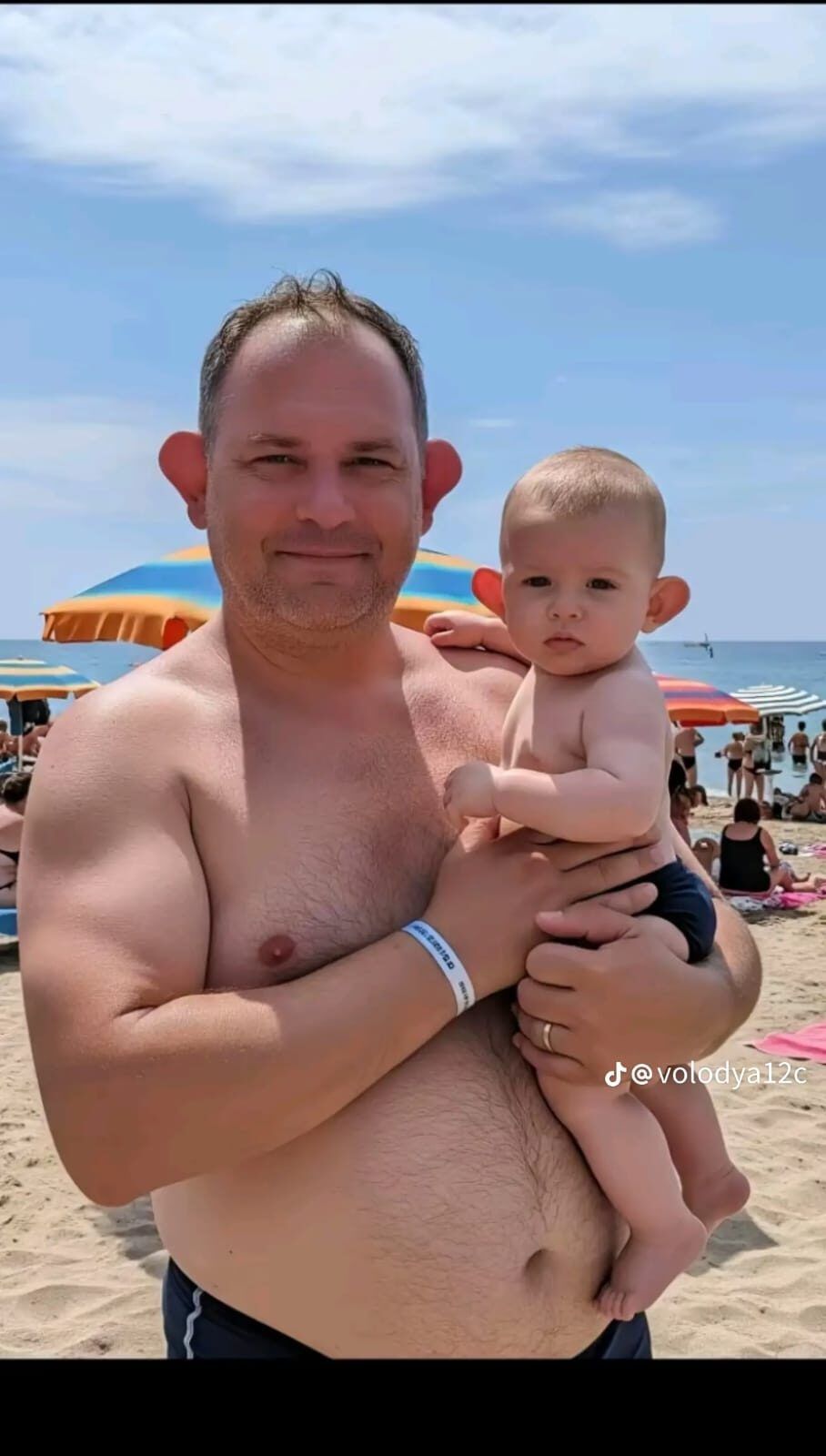 Мужчина на пляже держит маленького ребенка