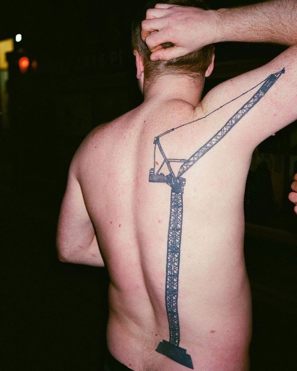 Мужчина без рубашки, на спине большая татуировка крана.