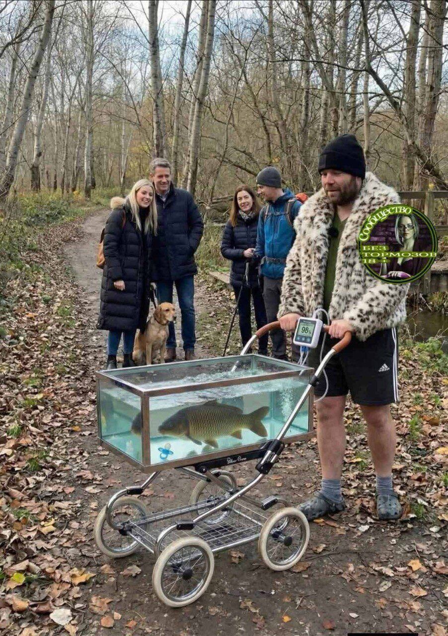Группа людей в парке наблюдает за переносным аквариумом на коляске с рыбой и собакой на поводке.